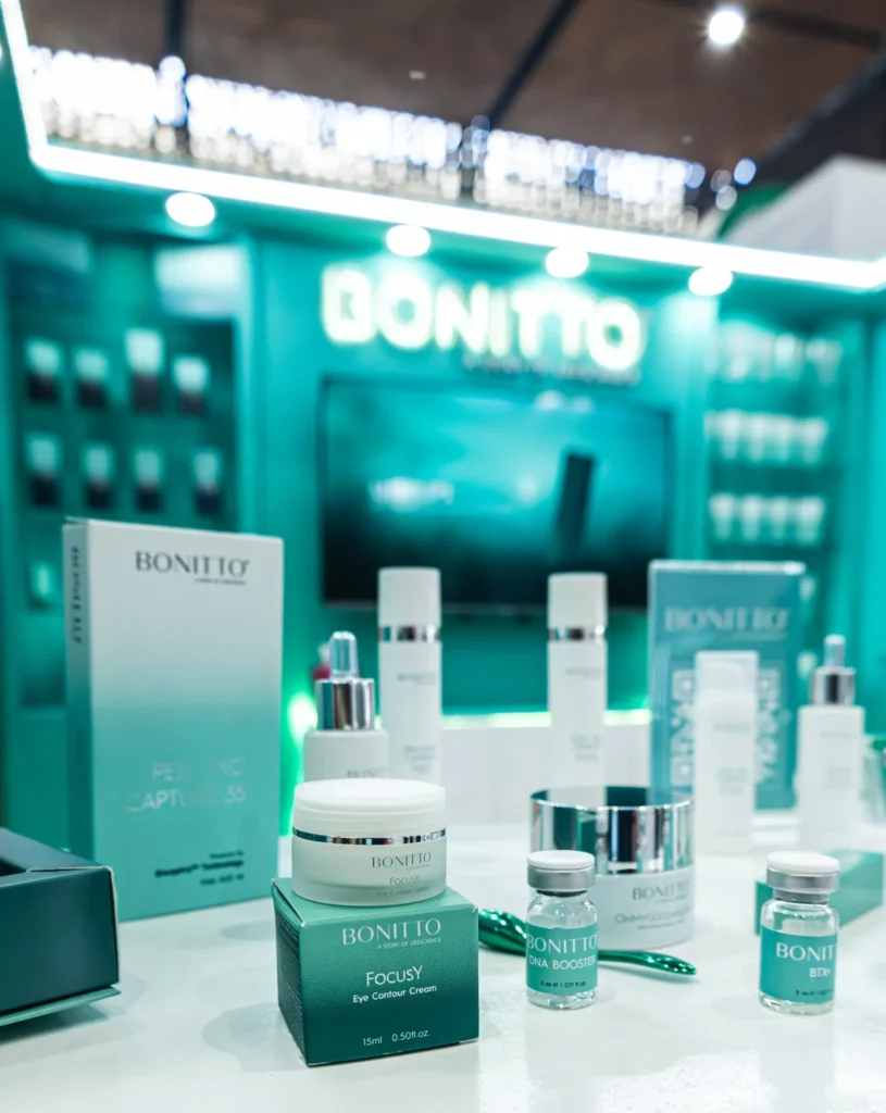 عرض لمنتجات BONITTO للعناية بالبشرة، بما في ذلك الكريمات والأمصال والعلب مرتبة على منضدة بيضاء مع خلفية بيضاء تحمل علامة BONITTO. يبدو المكان وكأنه في متجر أو كشك عرض.