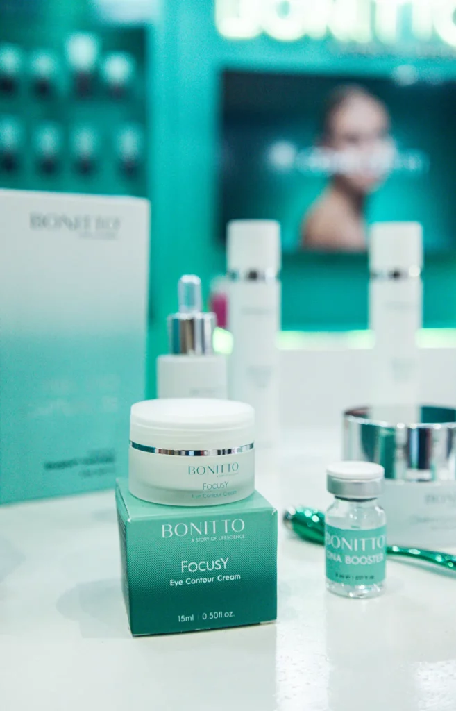 صورة مقرّبة لمنتجات بونيتو للعناية بالبشرة معروضة على سطح أبيض، بما في ذلك كريم فوكسي آي كونتور ومصل ميلا بوستر وزجاجات أخرى بخلفية غير واضحة تتميز بألوان الأزرق المخضر والأبيض.