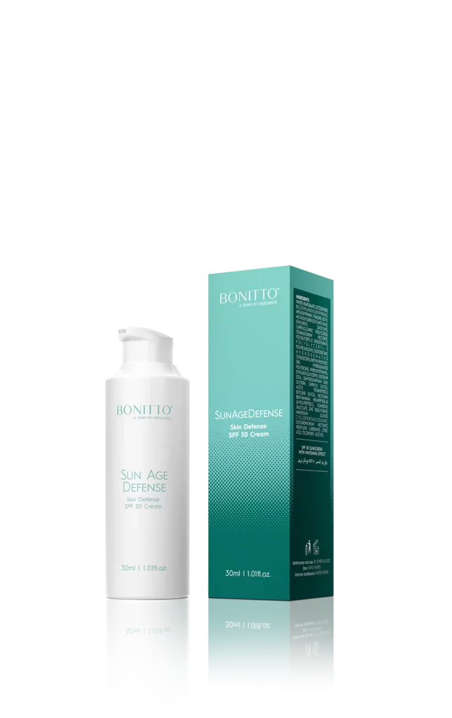 SUN AGE DEFENSE BOX new copia Un flacon blanc étiqueté "Bonito Sun Age Defense SPF 30 Cream" se trouve à côté de sa boîte rectangulaire sarcelle avec les détails du produit. Les deux contiennent 30ml (1.01 fl. oz.) de crème solaire.